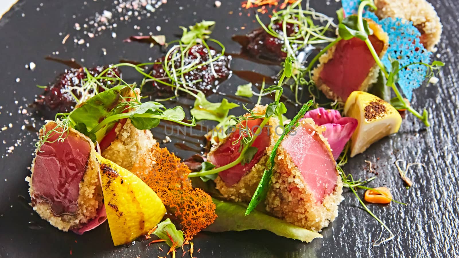 Close up of rare seared Ahi tuna slices with fresh vegetable salad on a plate. Shallow dof