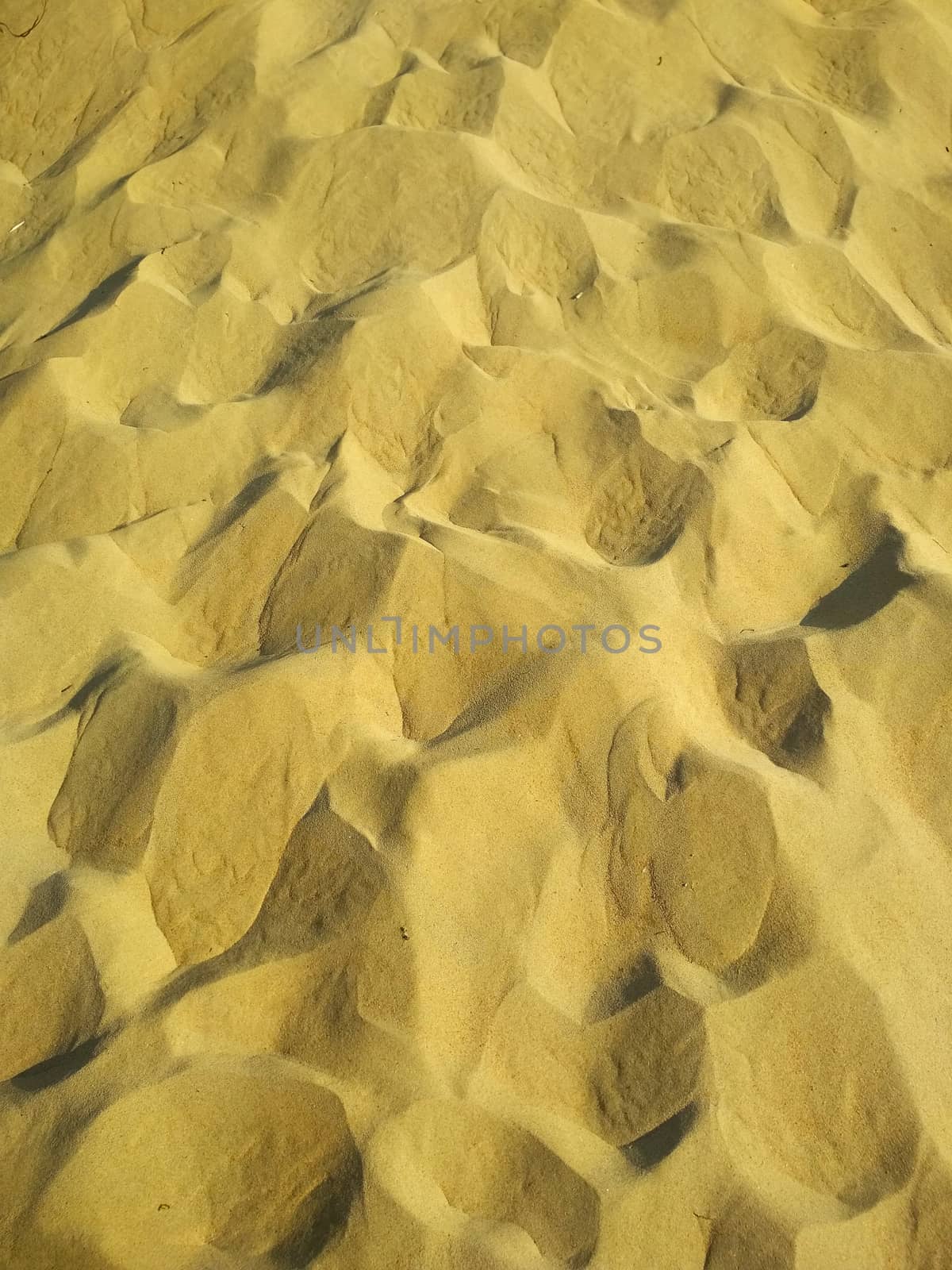 Texture of sandy soil with small pits and hills of yellow color.