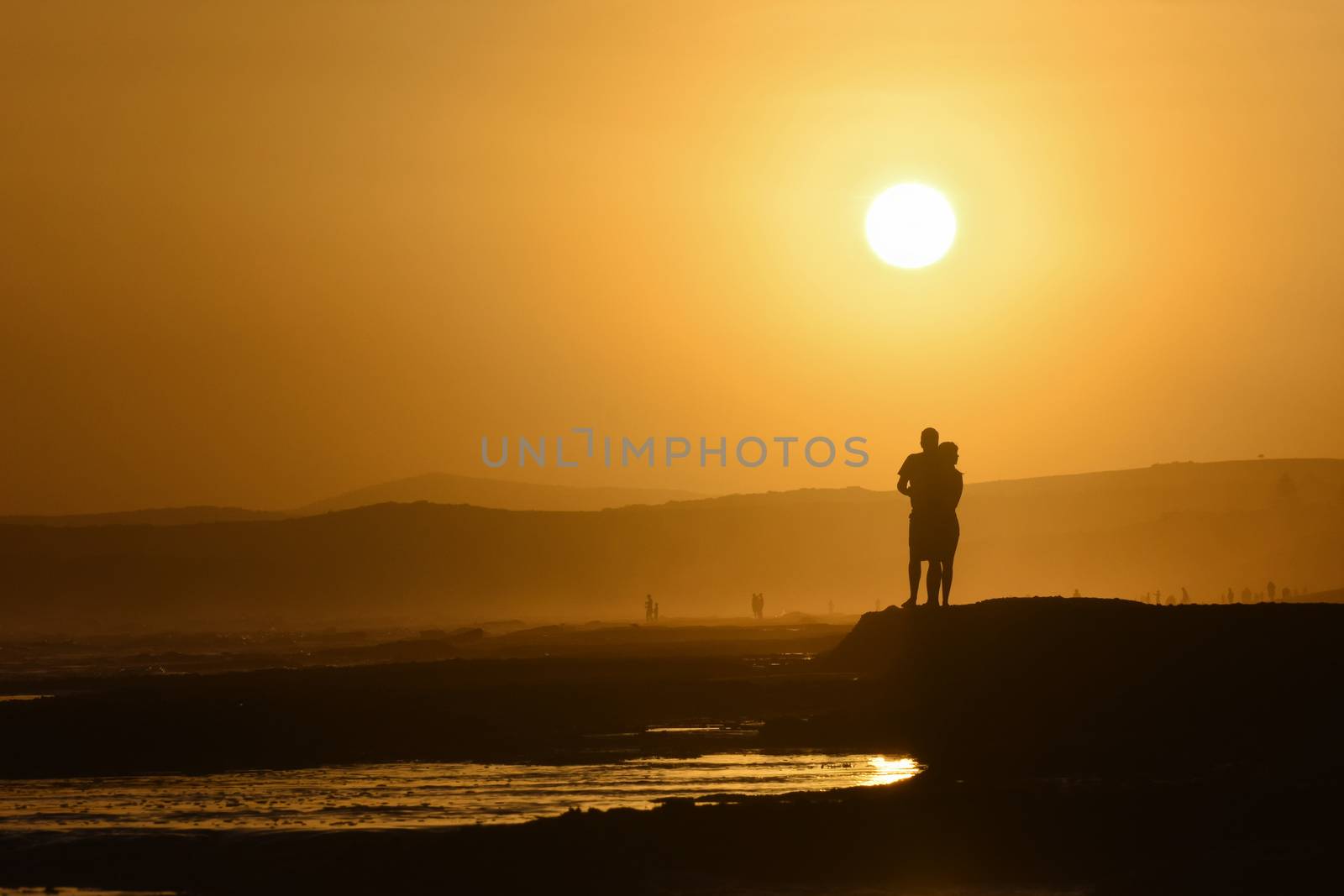 A young couple on the beach waiting for the sunset on a hot summer day, Mossel Bay, South Africa