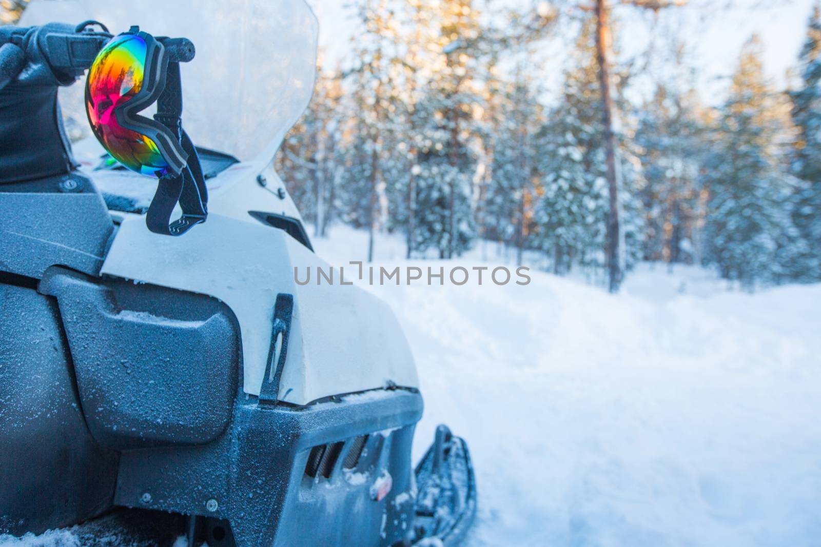 Snowmobile in winter snow forest in the morning side view and protective mask goggles glasses ready for adventure