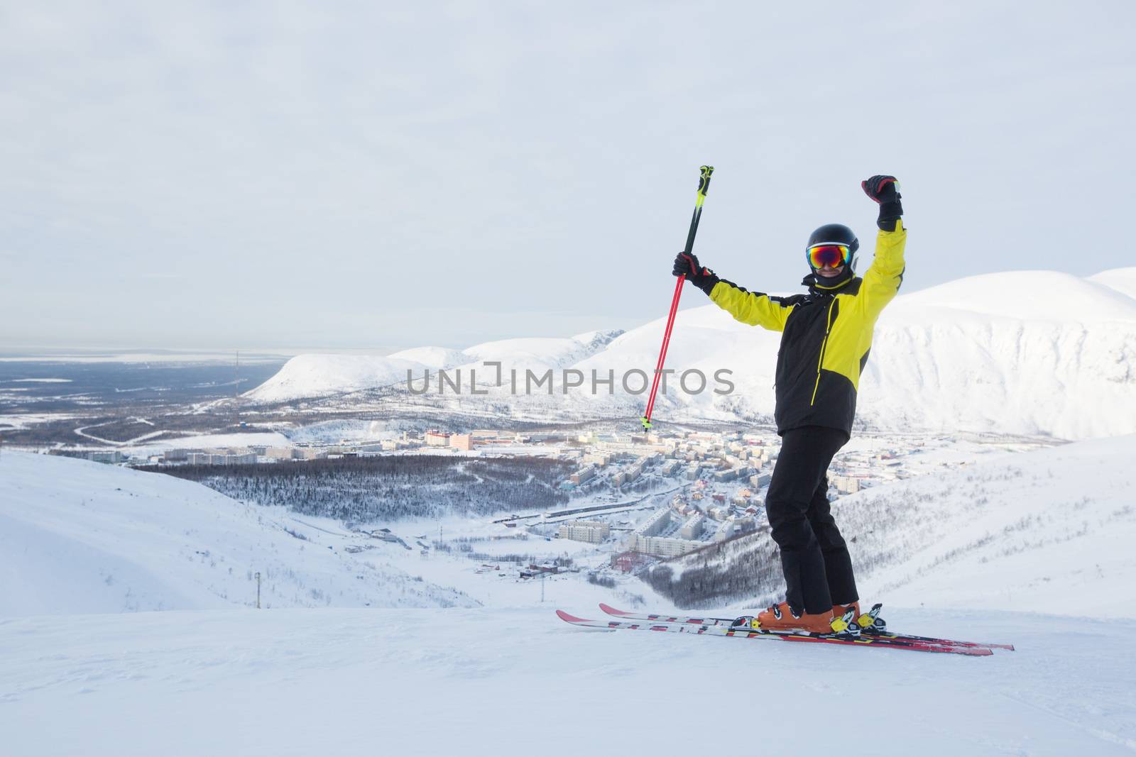 Kirovsk, Russia - Skier on piste in high mountains on ski slope. Rear view. Winter snowboard and skiing concept. Khibiny Mountains, Kola Peninsula panoramic view on town