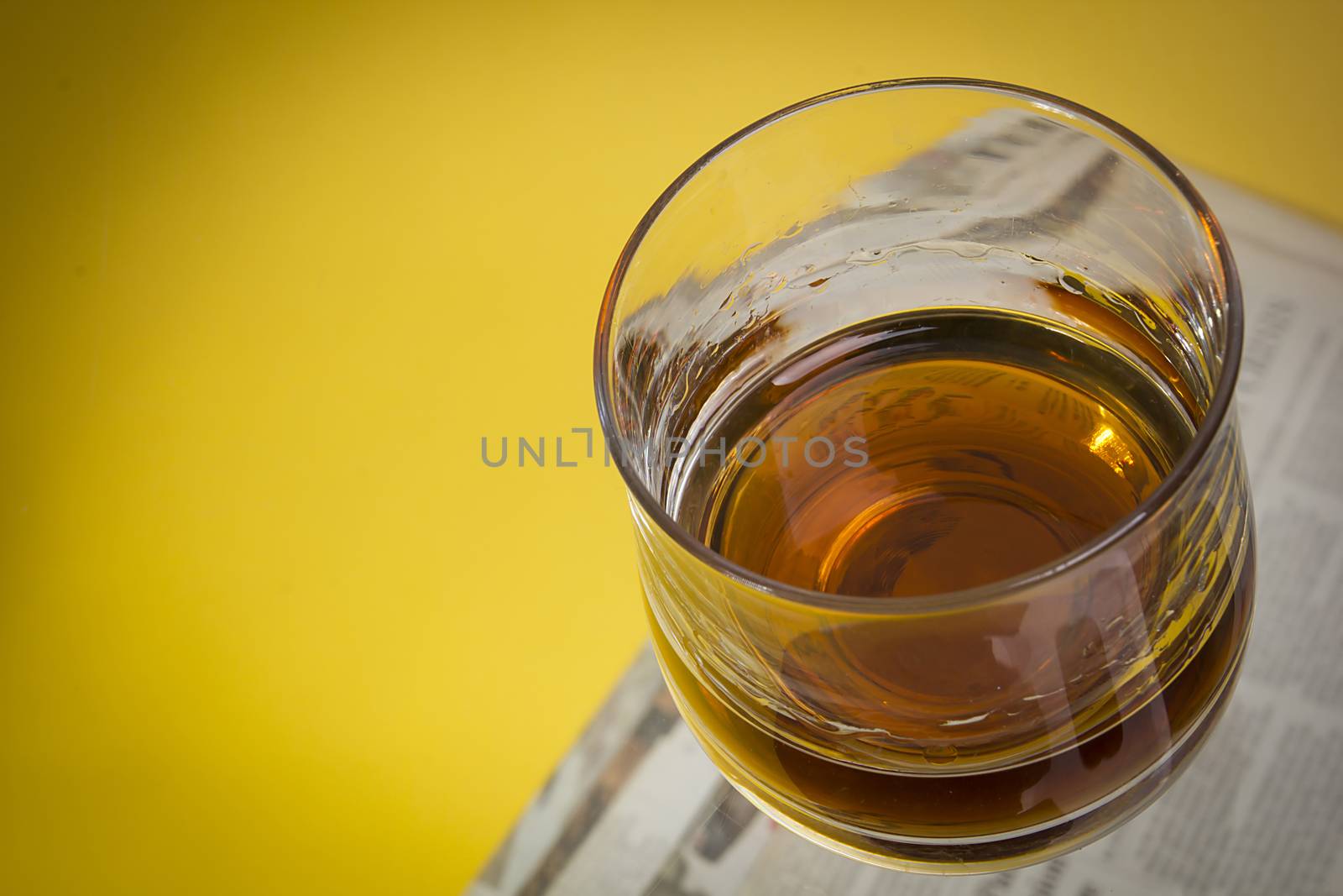 Glass with whiskey on a yellow background