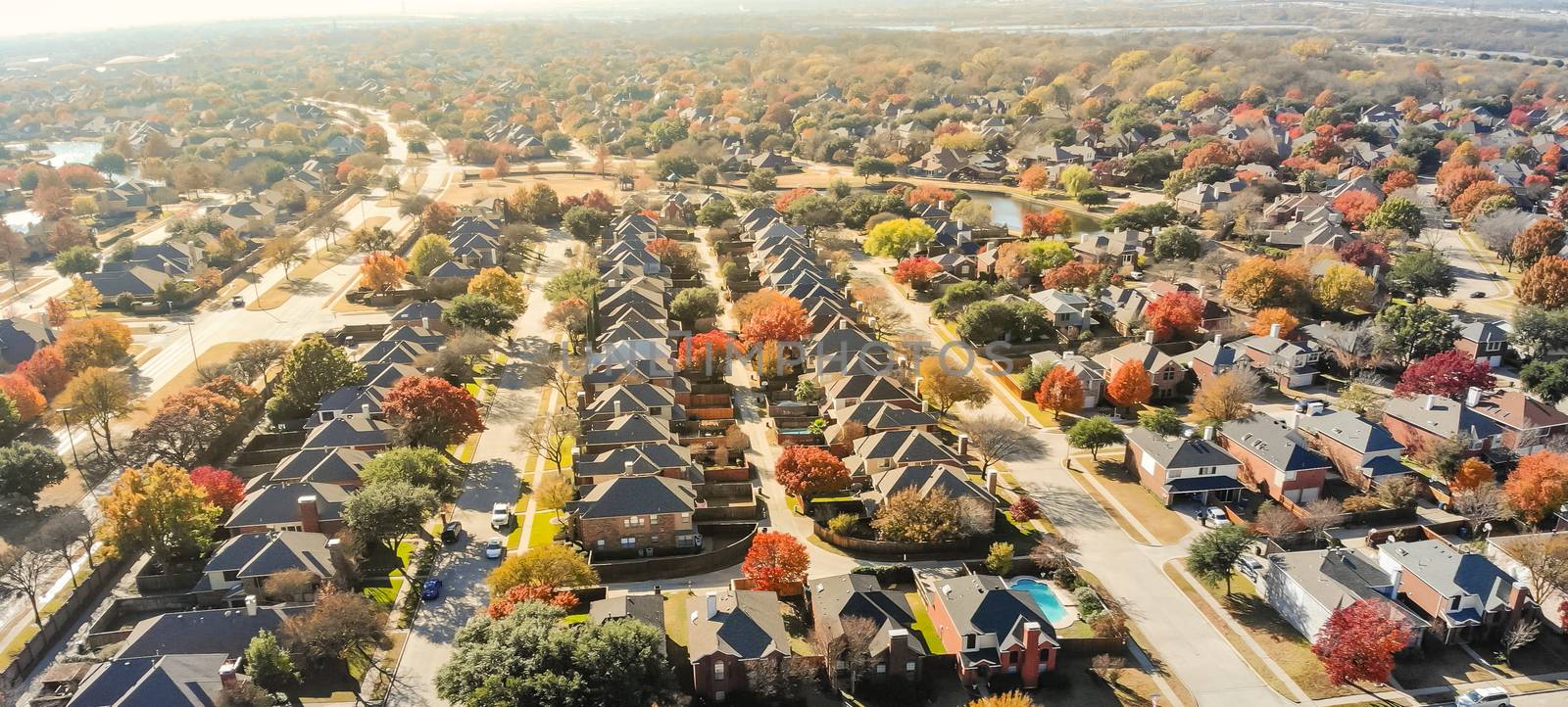 Panorama lakeside residential neighborhood in Dallas with new two story single family houses colorful fall foliage. Bright orange color along local street and drive way, beautiful Texas autumn scene