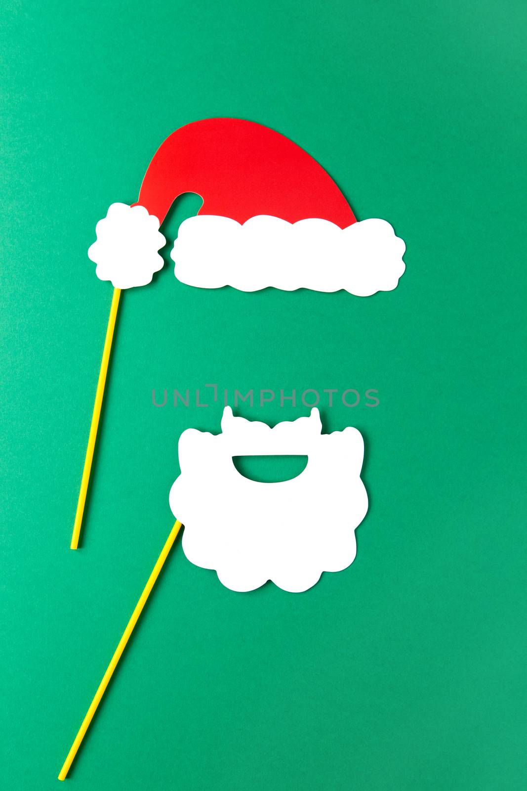 Christmas decoration, white beard and red Santas hat on sticks. Festive concept, party accessories. Vertical, flat lay. Minimal style. Top view.