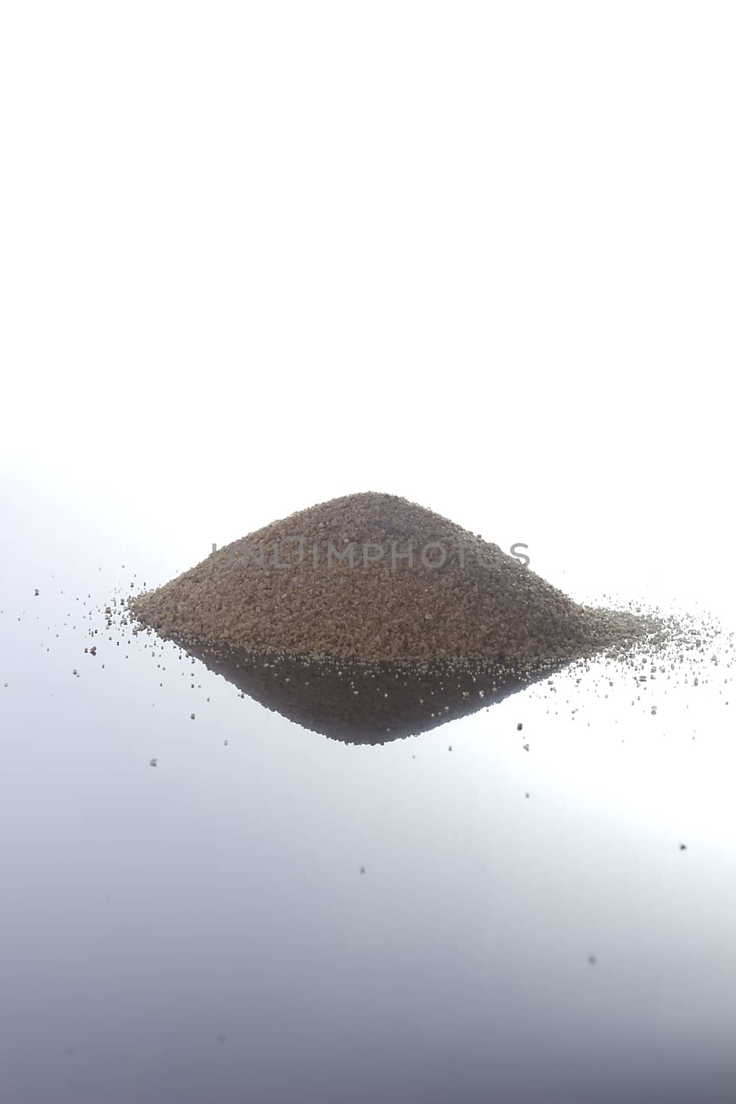 Pile of sand on a white reflective surface on a white surface