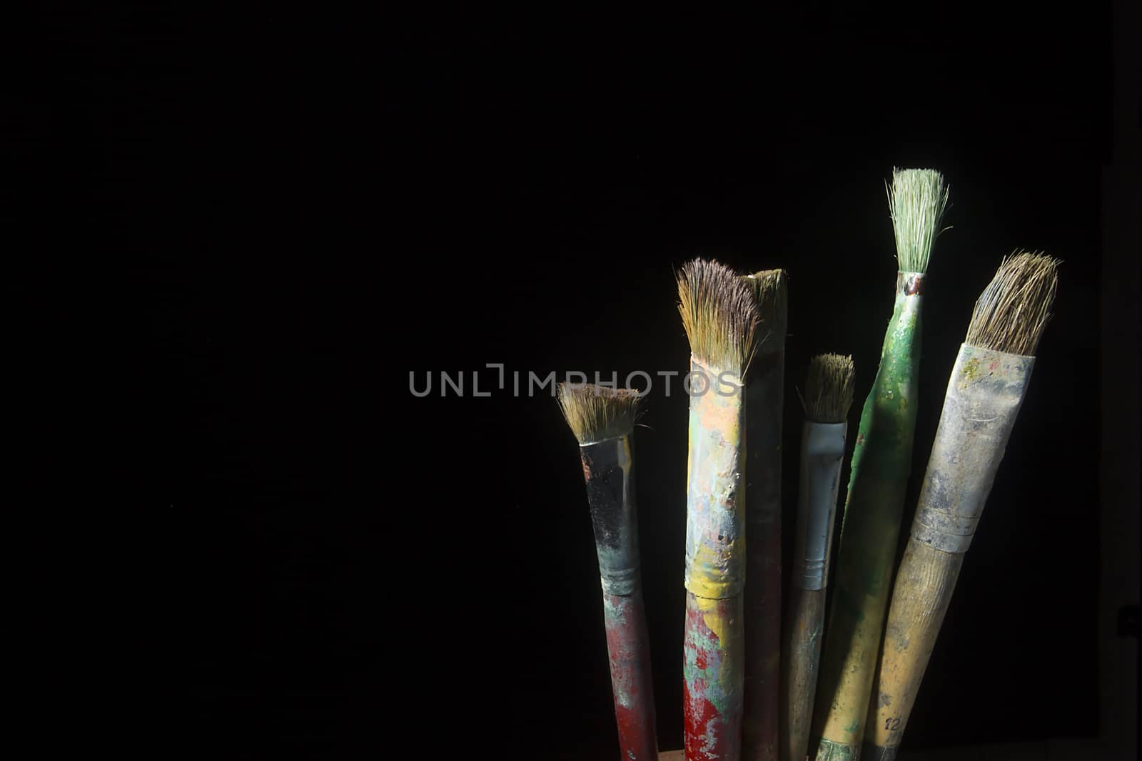 Artist's brushes in paint on a black background