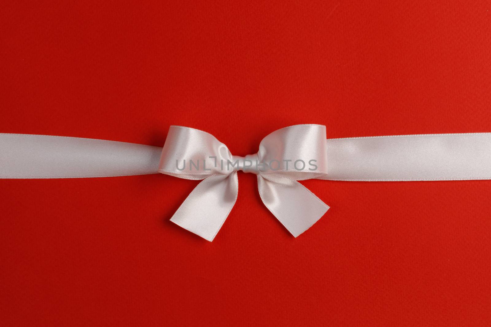 White gift bow on red background copy space for text