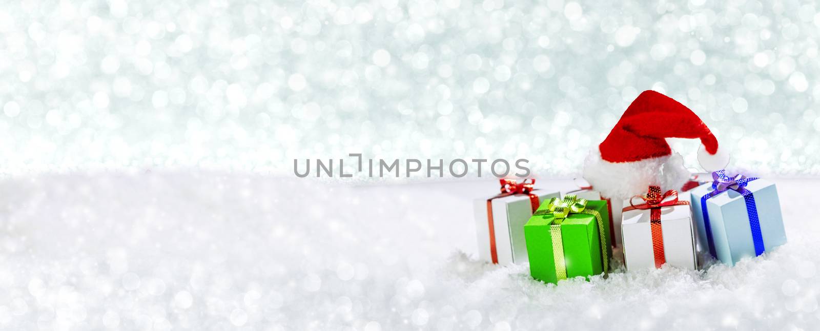 Christmas holidays card with small gifts and santa claus hat in snow