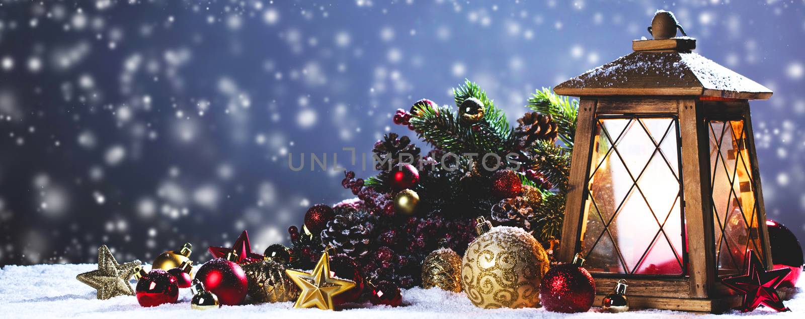 Burning candles , lantern and christmas decoration on snowfall background