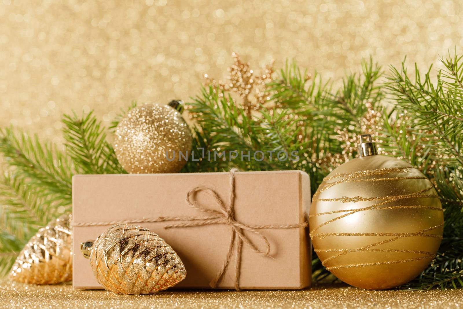 Christmas toys, decorations, present gift box wrapped in kraft paper on golden glitter background, copy space
