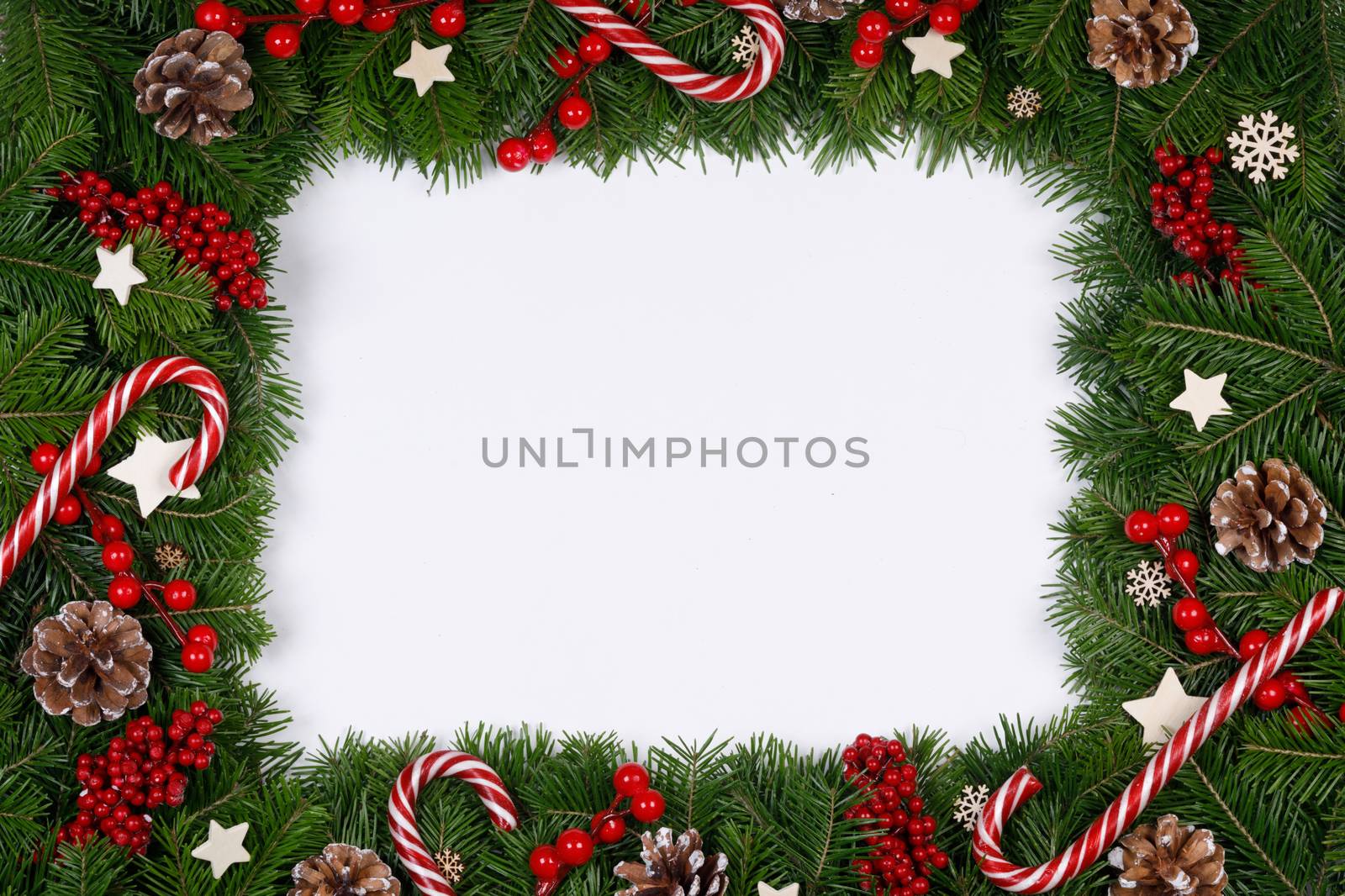 Christmas Border frame of tree branches on white background with copy space isolated, red and white decor, berries, stars, cones