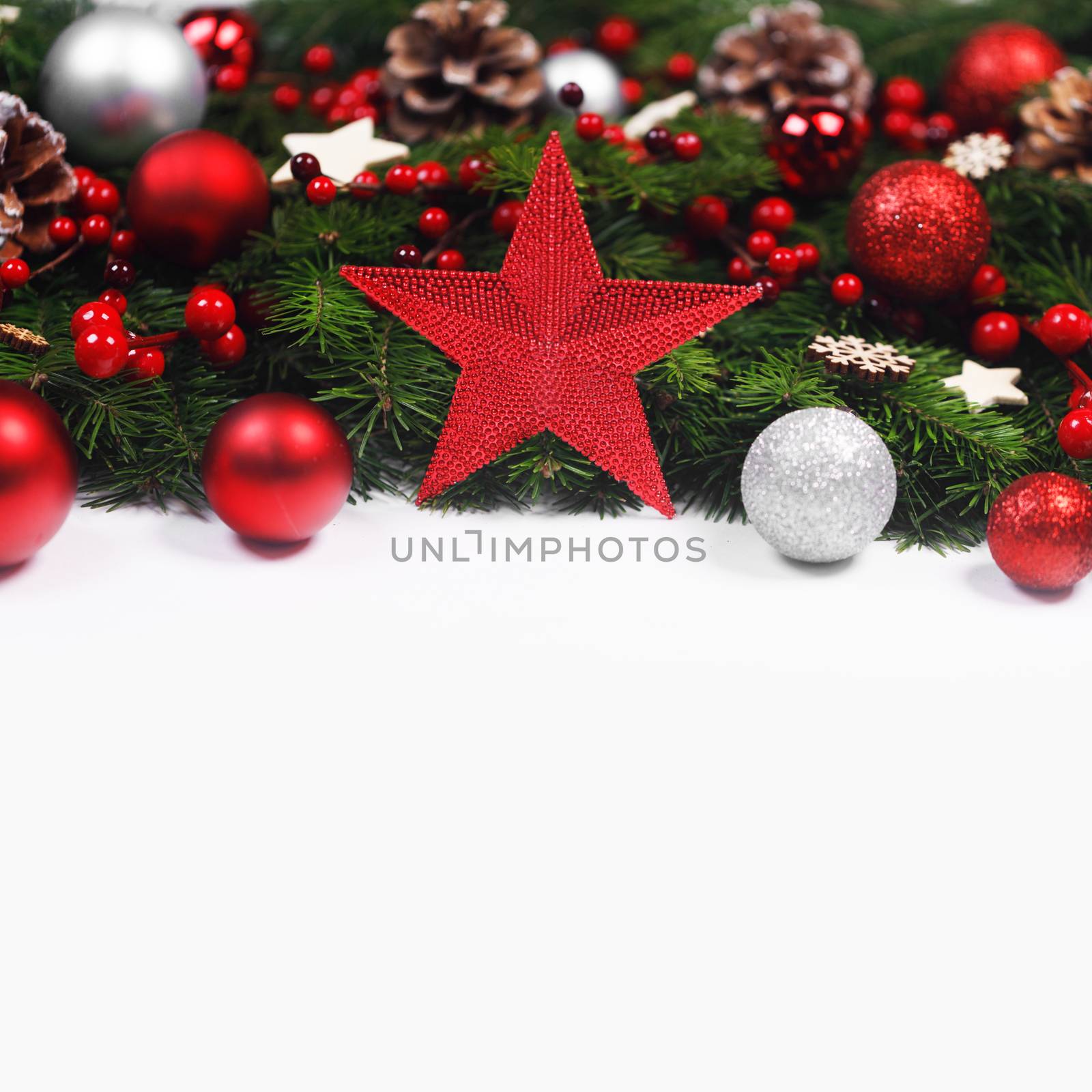 Christmas Border frame of tree branches on white background with copy space isolated, red and silver decor, berries, stars, cones