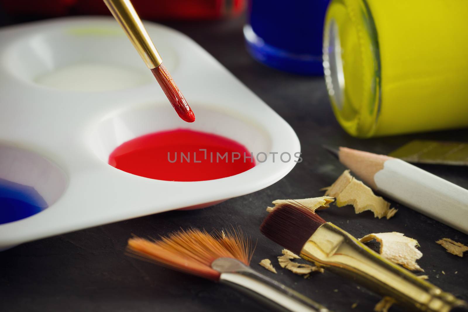 Closeup artist paint brush above color plate and poster color bo by SaitanSainam