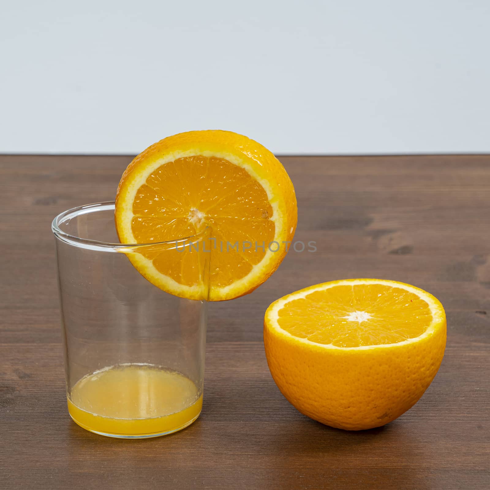 An orange fruit sliced and a glass on a wooden surface