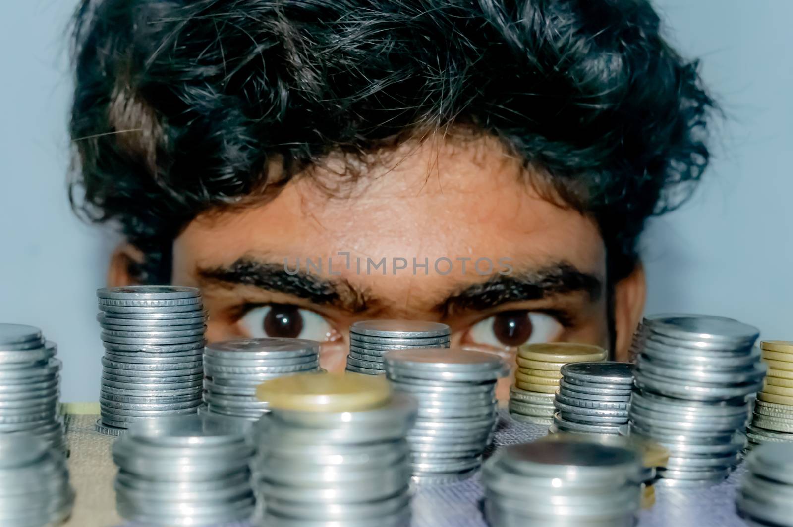 Businessman looking at stack of currency. Concept of a greed gesture. Closeup. Focus on Foreground Coins. by sudiptabhowmick