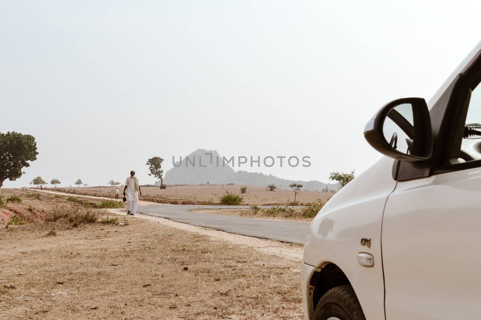 Mid adult Poor Indian village people walking alone in an empty road in a scorching hot summer day. A car point of view image. A Bihar India tourism photography. by sudiptabhowmick
