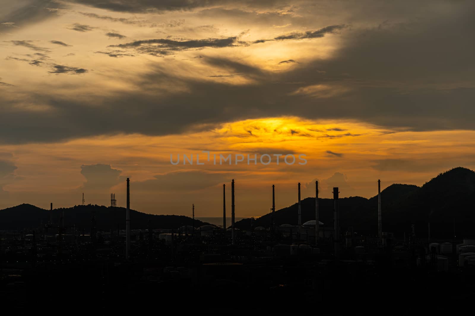 Oil Or Gas Refinery At Sunset. A silhouette of an oil or gas industrial refinery at sunset with a colourful sky behind by peerapixs