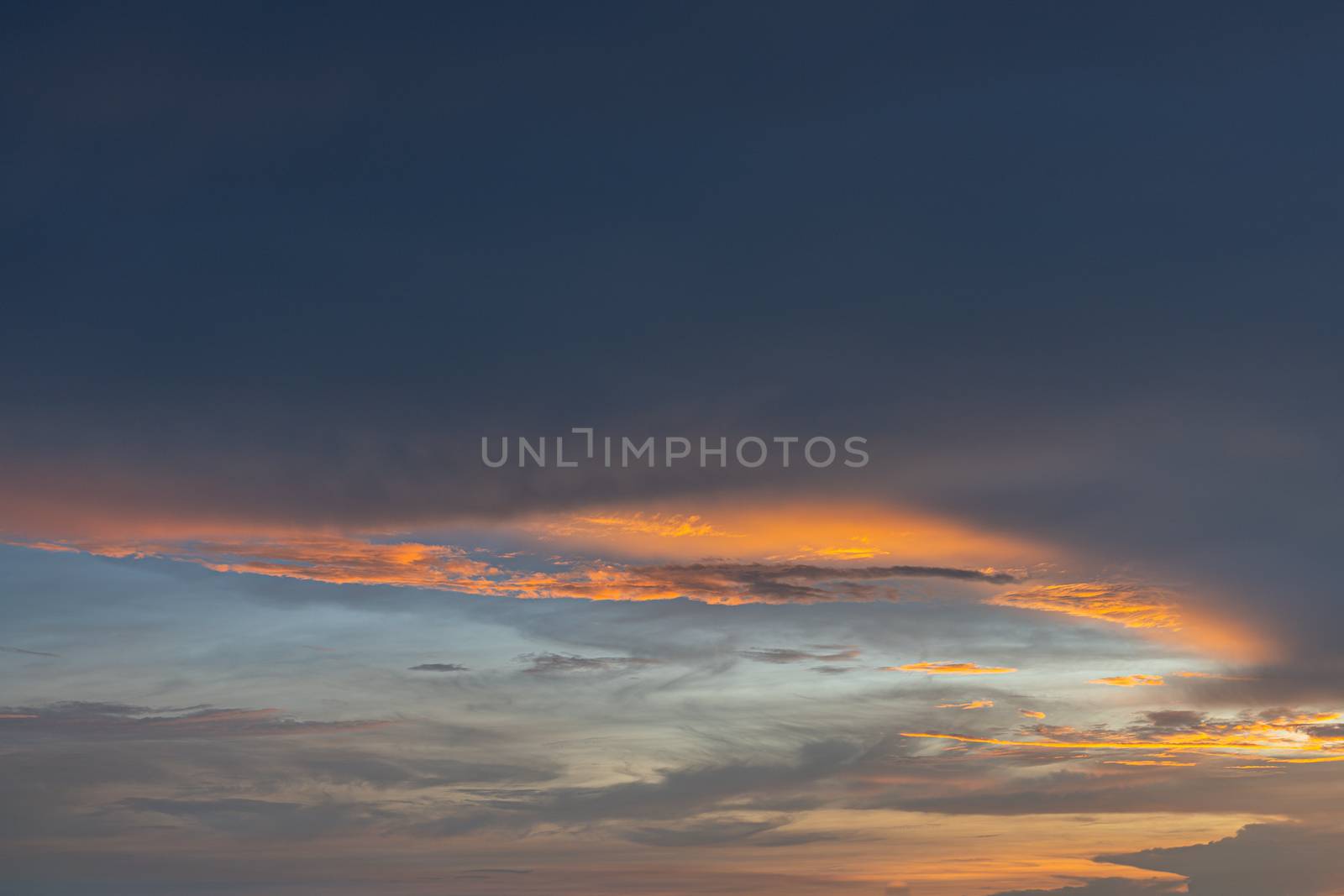 Bright orange and gold colors of the sunset sky. Summer sky with clouds during the sunset by peerapixs