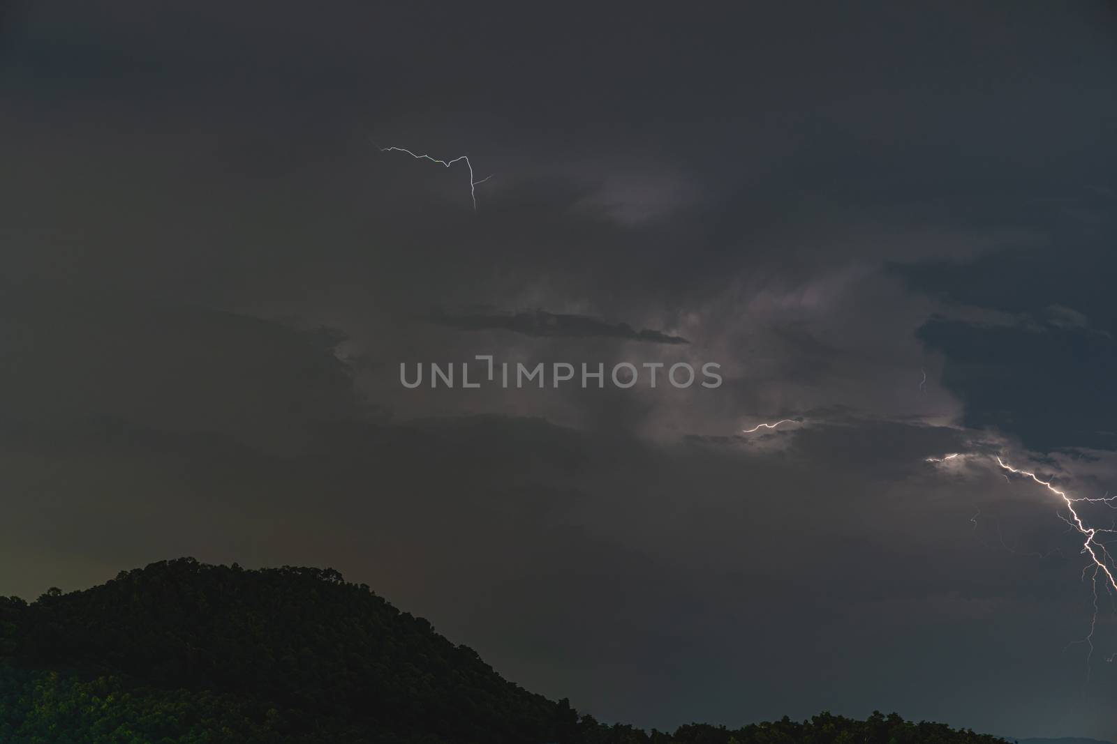 Storm lightning strikes in mountains during a thunderstorm at night. Beautiful dramatic view by peerapixs