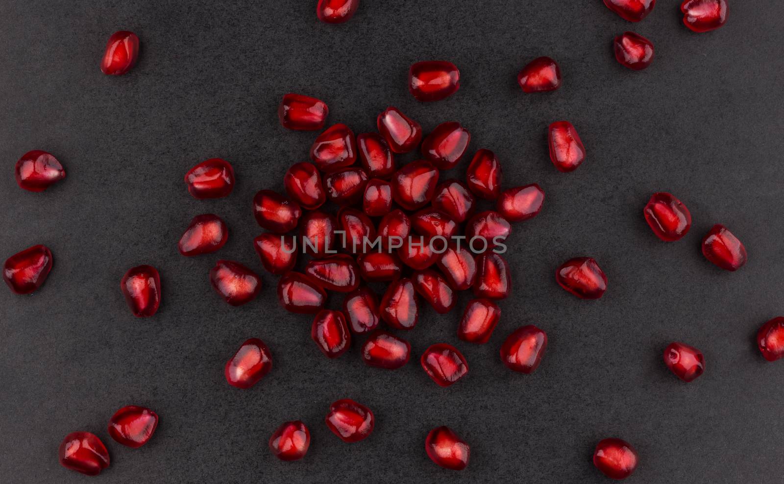 Pomegranate seeds on black background, top view