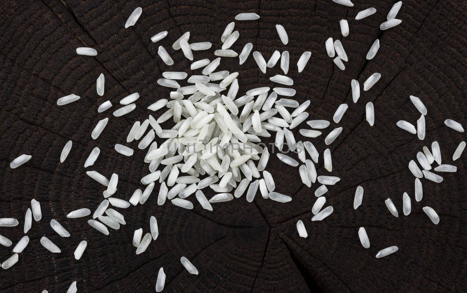 Heap of rice groats on black wooden background, top view