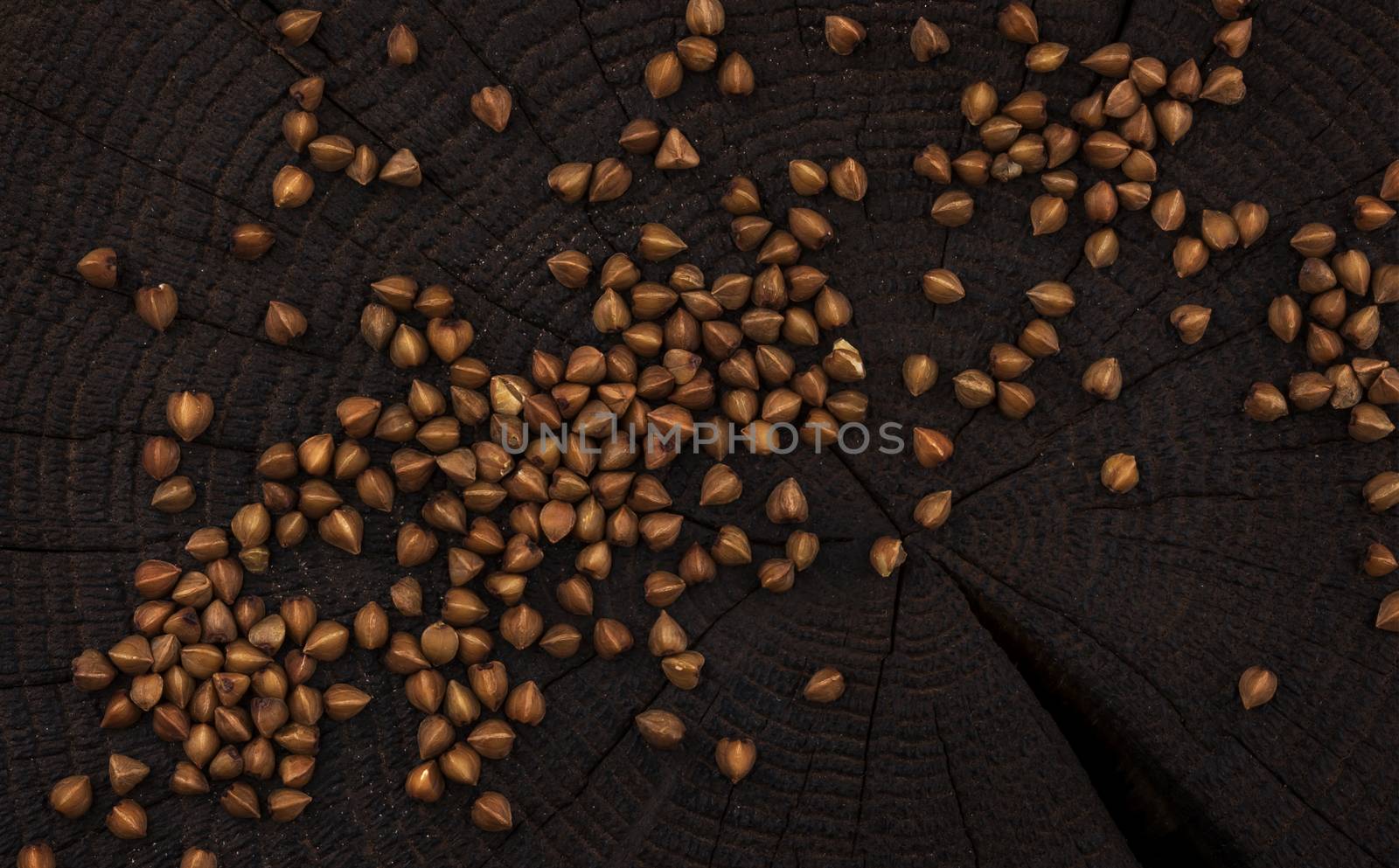 Heap of buckwheat grain on black wooden background, top view