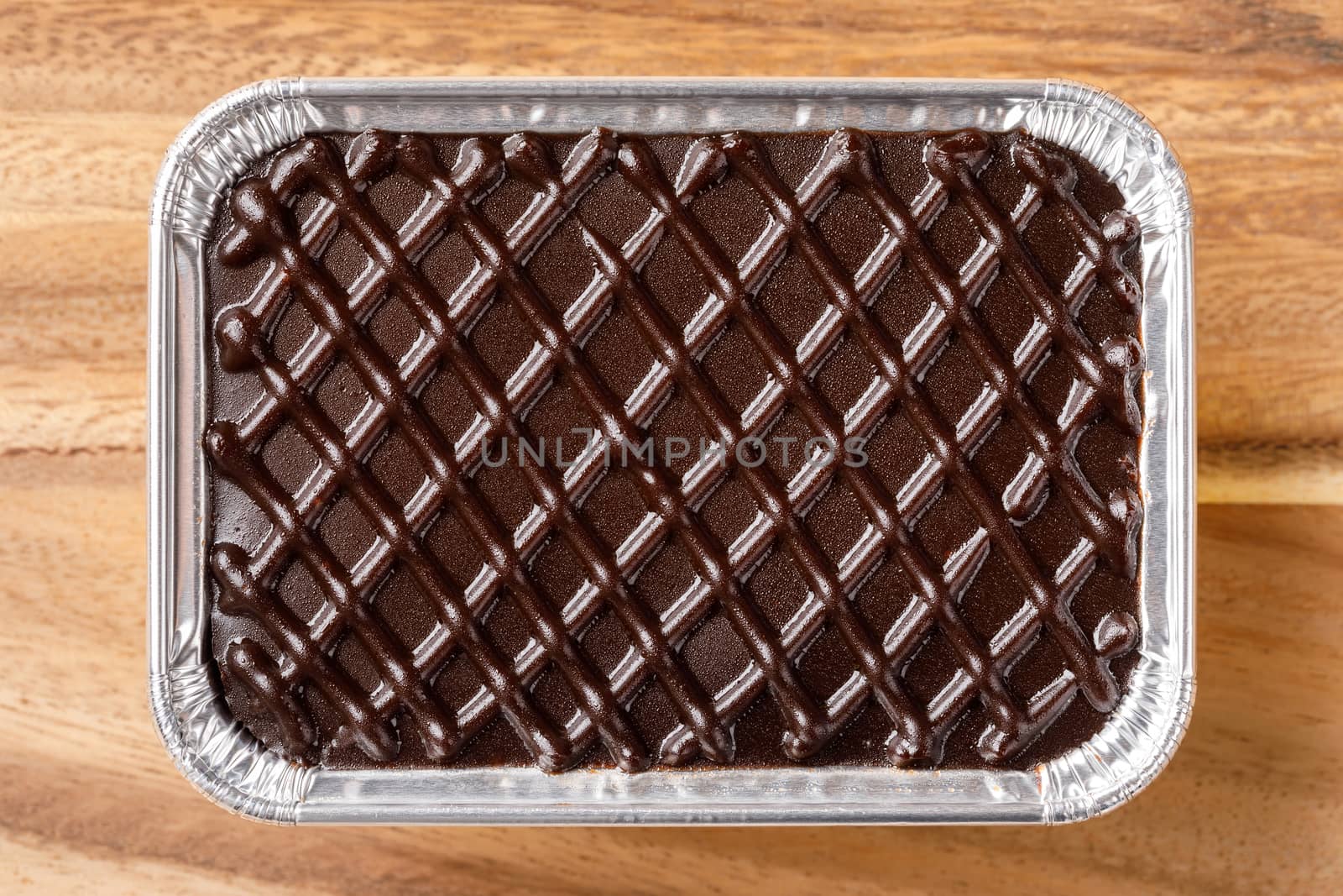Chocolate cake in aluminium foil tray on wooden table or cutting board