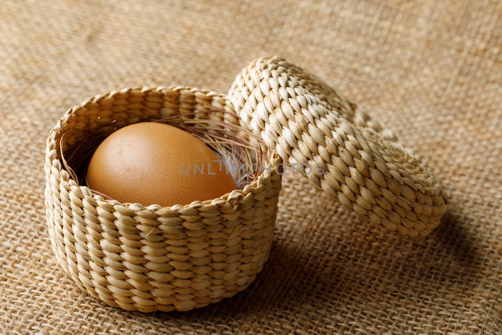 Chicken or hen egg in wicker basket on sackcloth by smuay