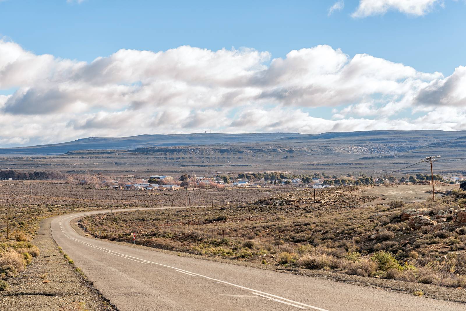 View of road R356 with the town of Sutherland in the back. A radar station is visible on the mountain in the back