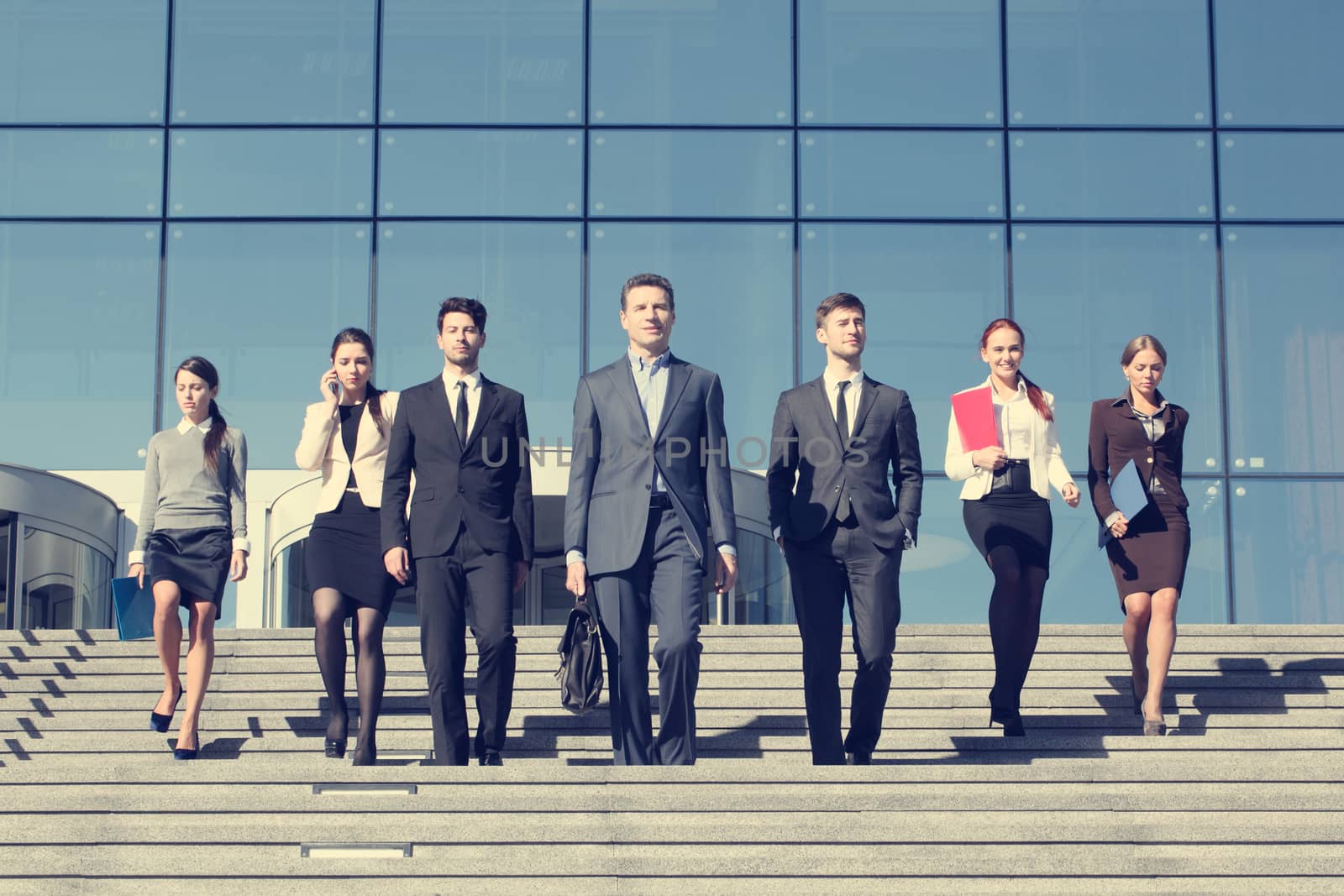 Group of business people walking down stairs in front of office building