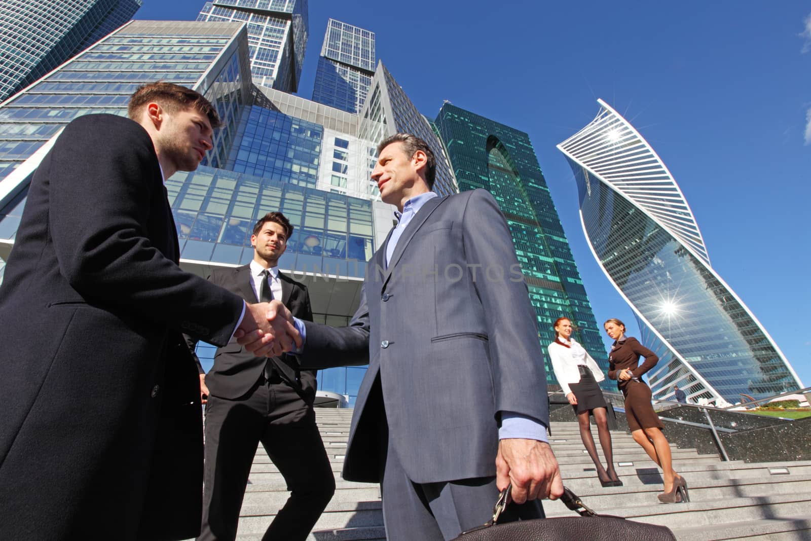 Business people shaking hands, finishing up a meeting outside office outdoors