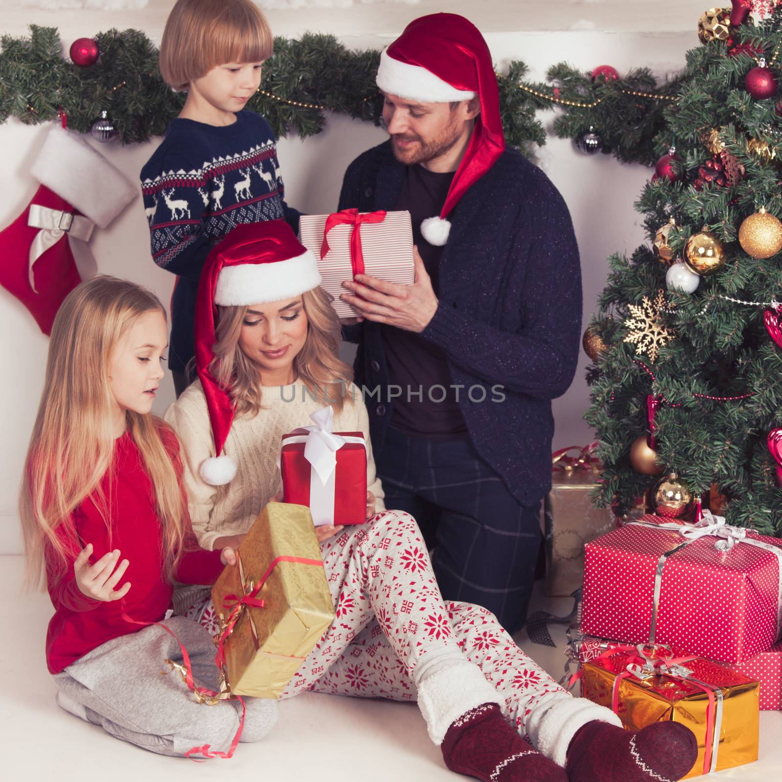 Cheerful family with Christmas gifts sitting near decorated Christmas tree