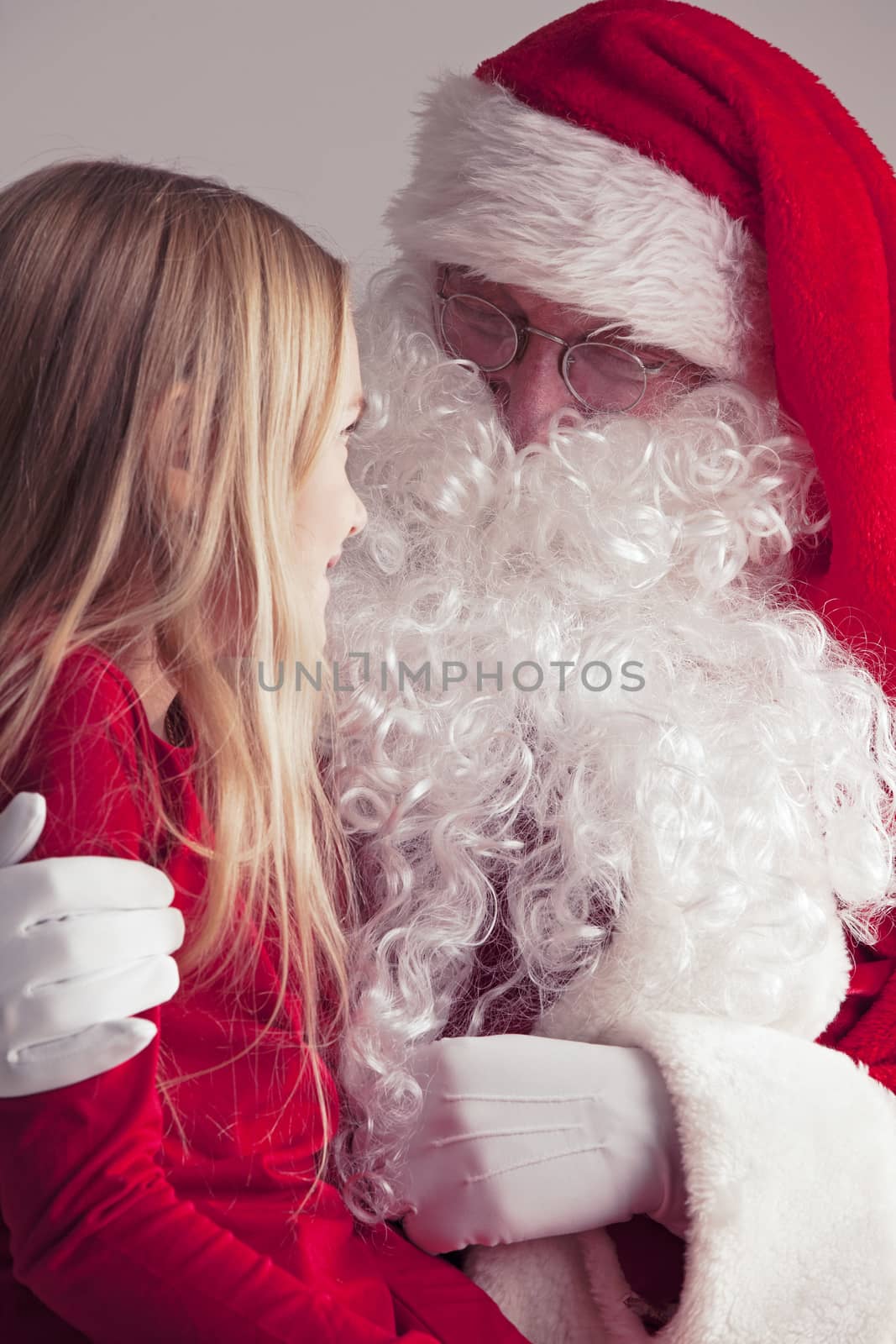 Little girl sitting on santa claus knees and talking to him