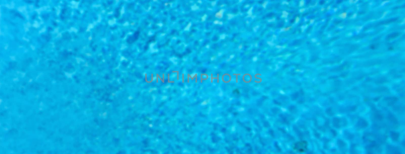 Defocused background with blue water surface of a swimming pool. Intentionally blurred post production for bokeh effect