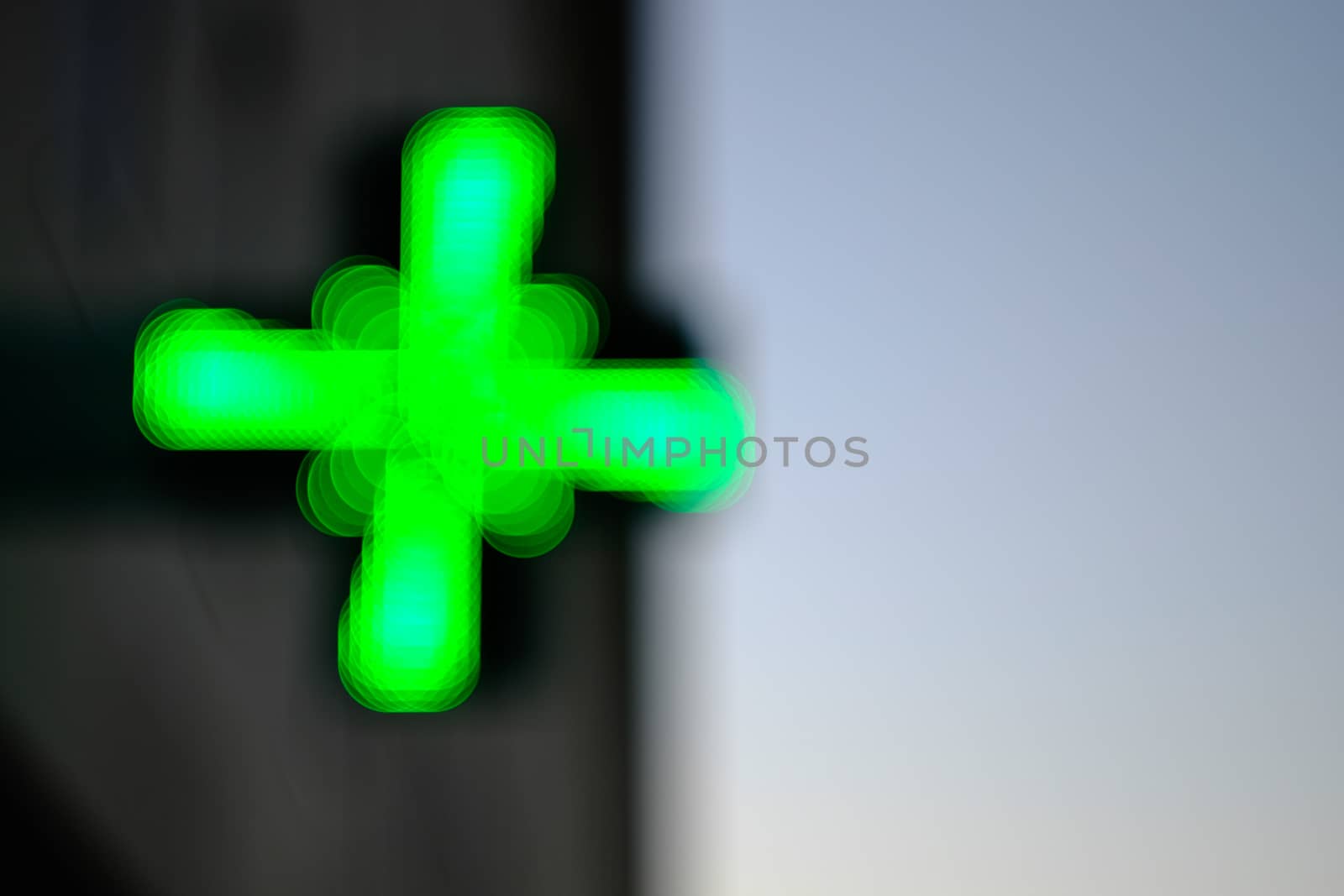 Pharmacy green cross blurred over light and dark background by mikelju