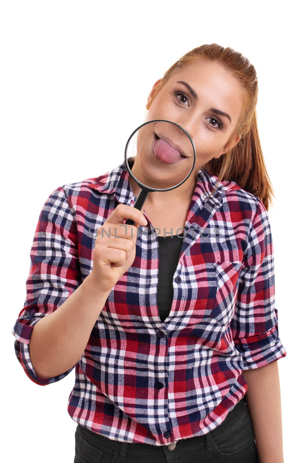 Beautiful young woman showing her magnified tongue under magnifying glass. Portrait of a smiling young girl sticking her tongue out, looking at camera, isolated on white background.
