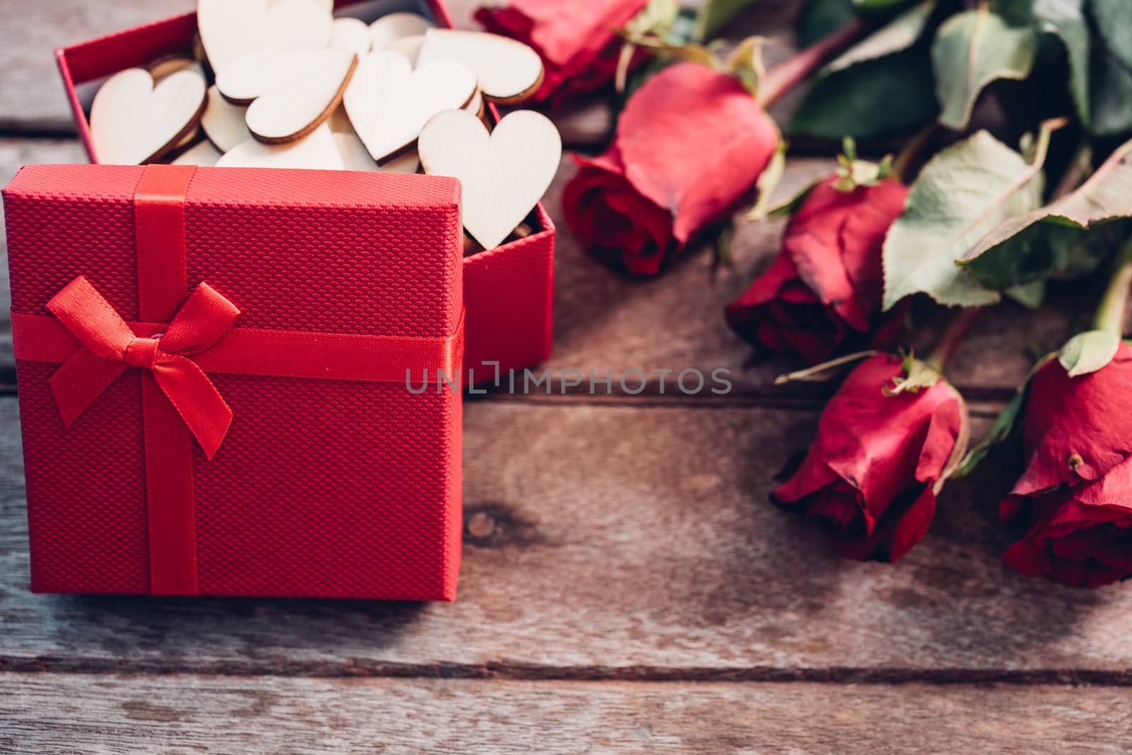 Flower roses and red gift box on wooden background by Sorapop