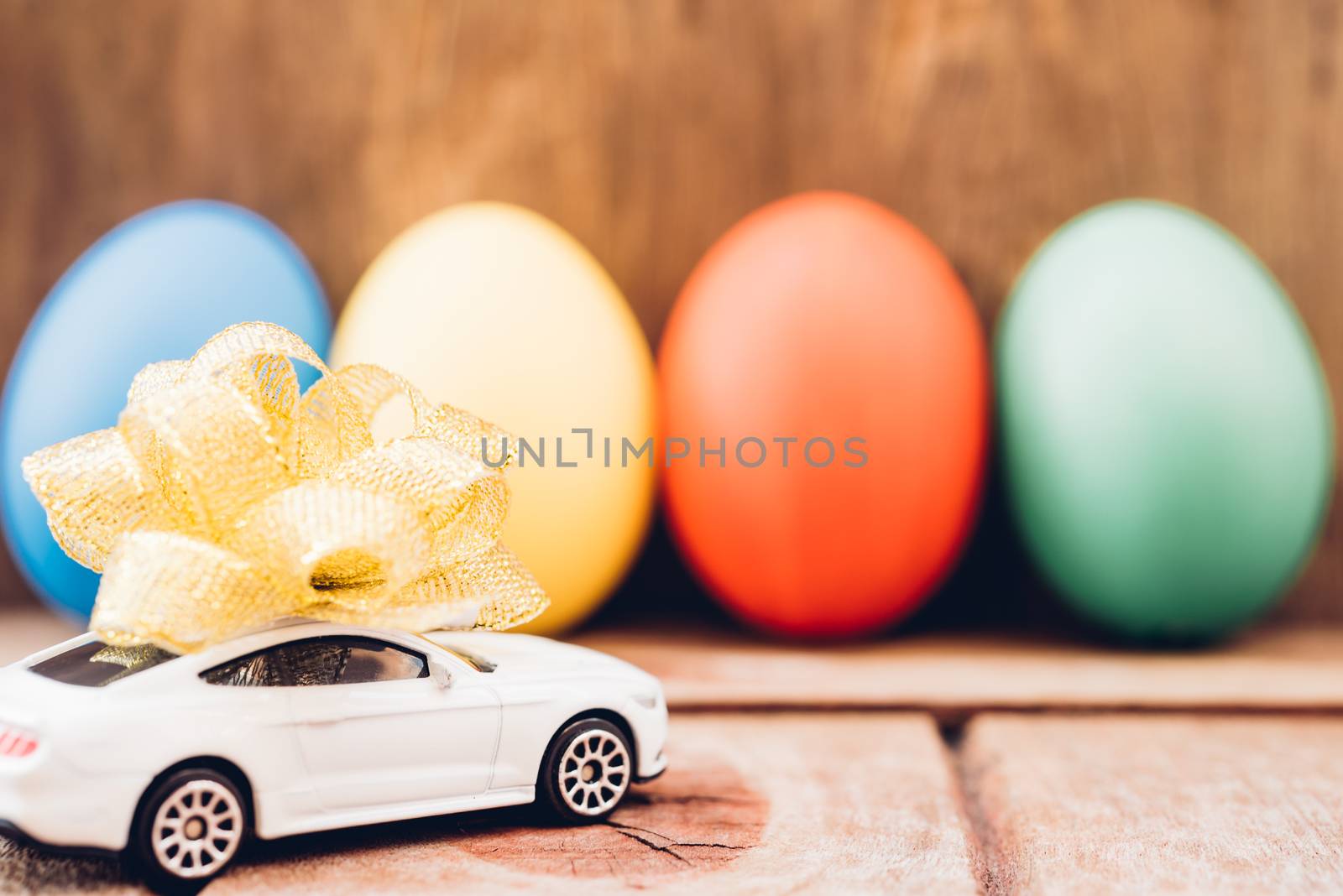 Easter egg and toy car on wooden background, happy easter day concept