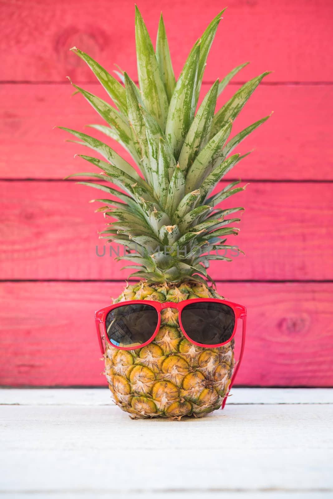 Holiday pineapple on red wooden background, tropical holiday concept