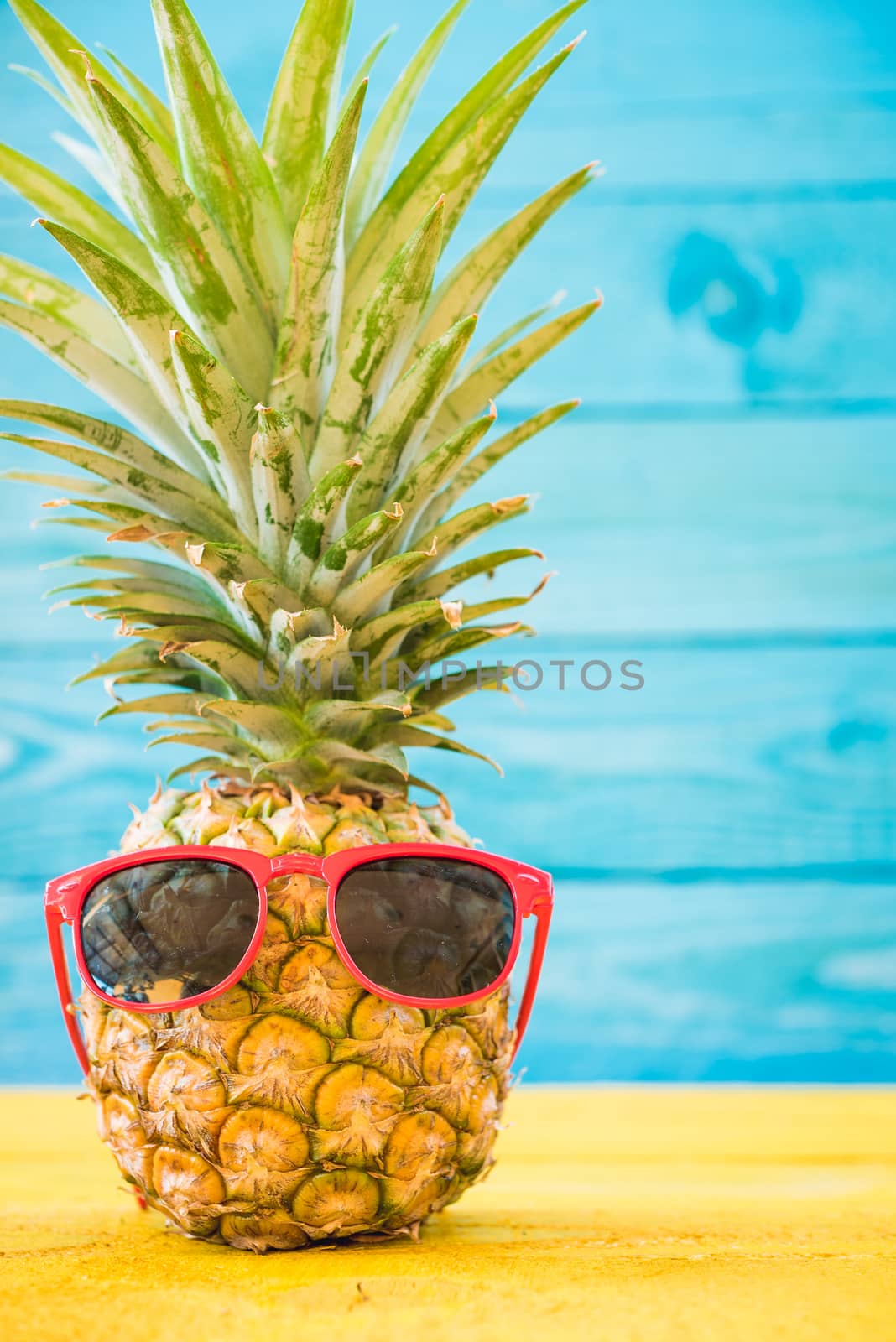 Holiday pineapple have sunglasses on blue wooden background, tropical holiday concept