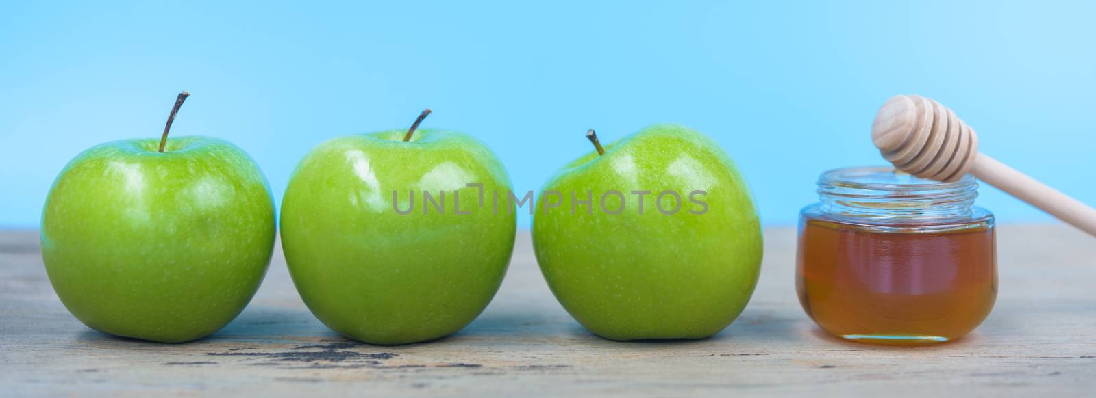 Jewish holiday, Apples Rosh Hashanah on the photo have honey in jar and green apples on wooden with blue background