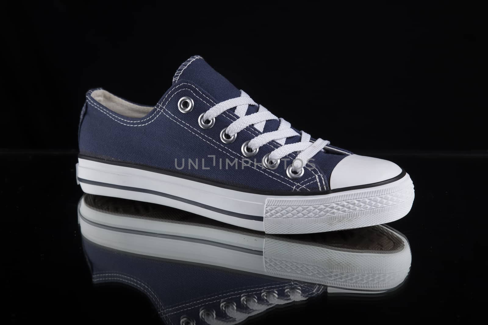 Blue and white sneaker on black background, isolated product.