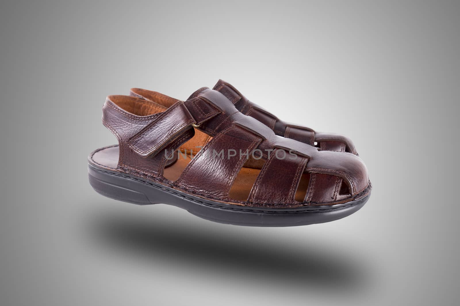 Pair of brown leather sandal on grey background, isolated product.