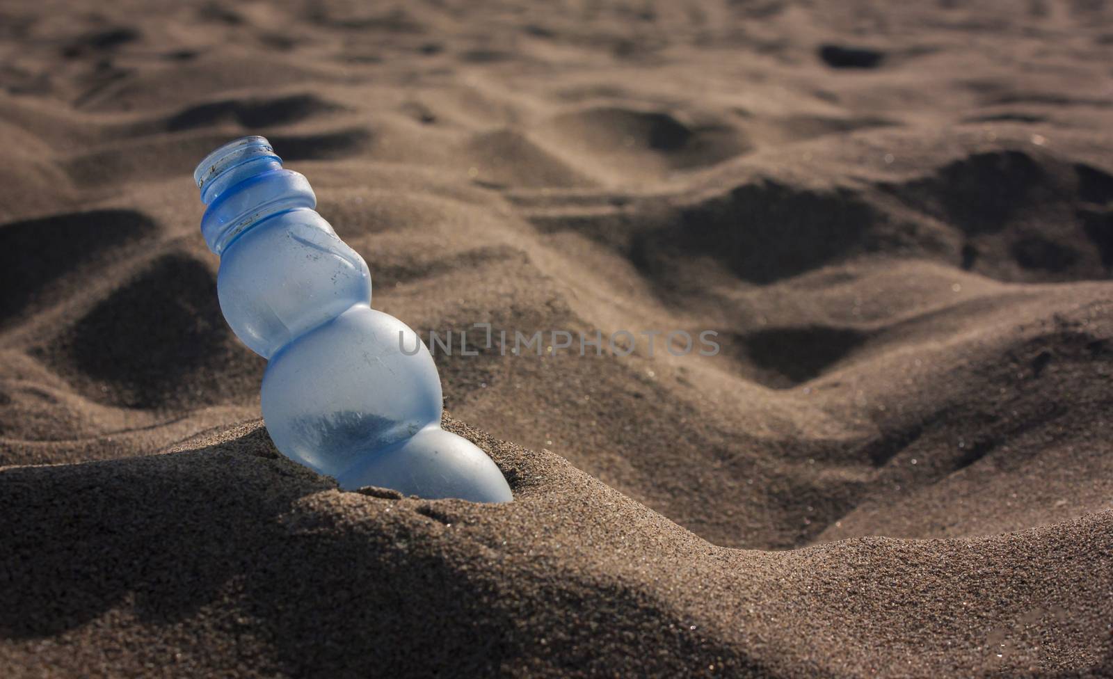 Pollution: a stranded Plastic waste on the sand of a beautiful Italian beach
