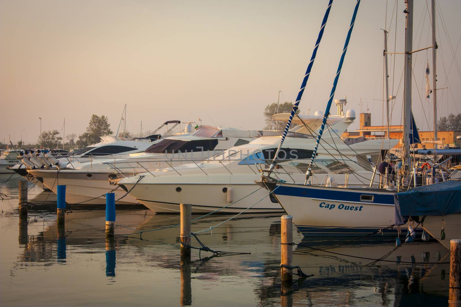 View of several boats moored on the great port of Albarella in Italy, illuminated by the warm colors of dawn