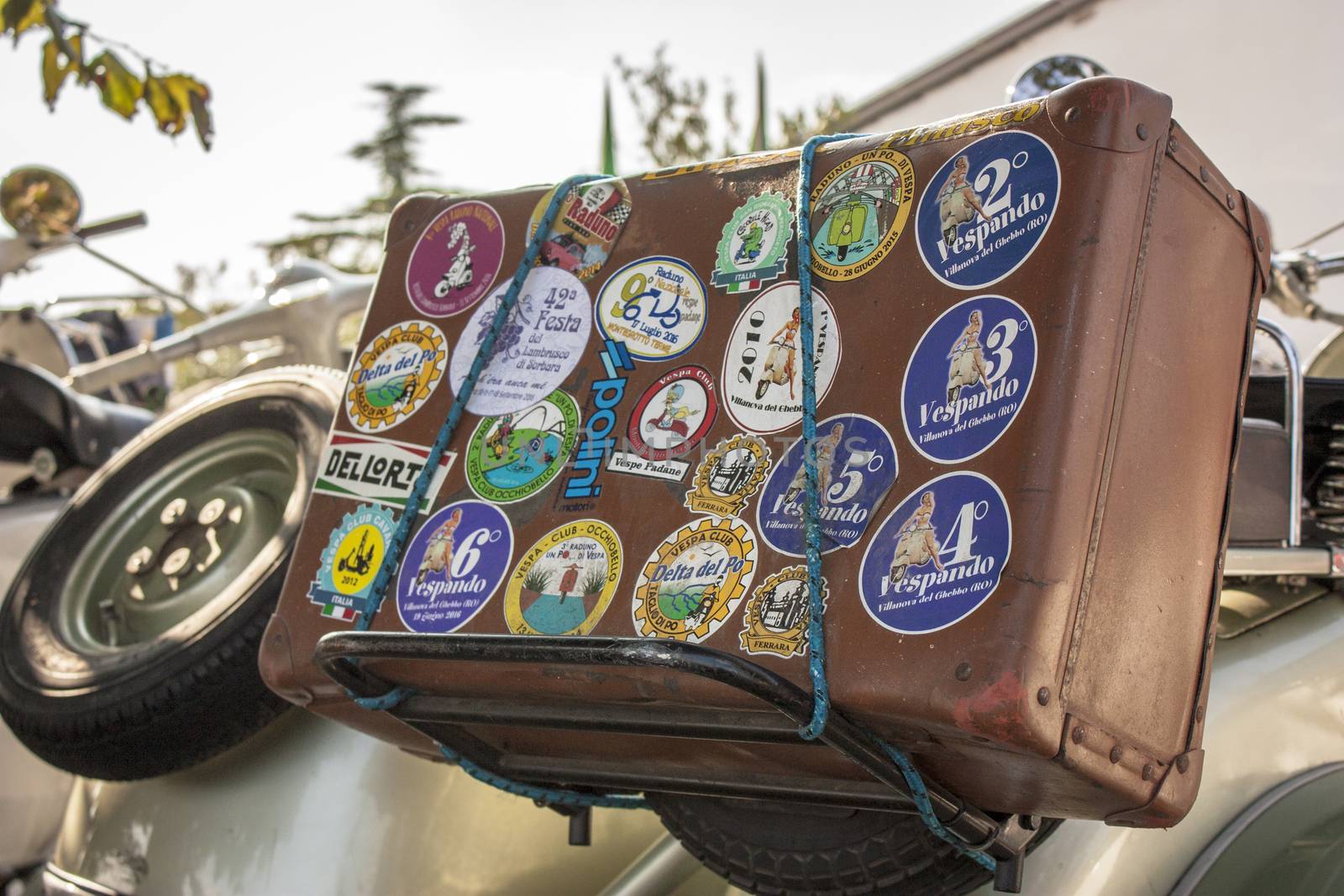 vintage suitcase tied on the luggage rack of a Vespa history. The emblem of Italian traditions. An old way of traveling.
