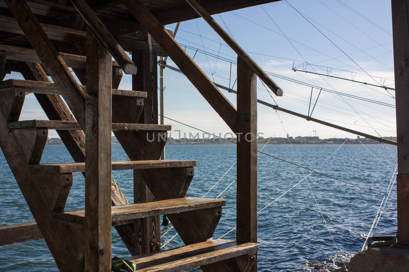 Wooden staircase a rustic restaurant on a dam in the sea in Italy.