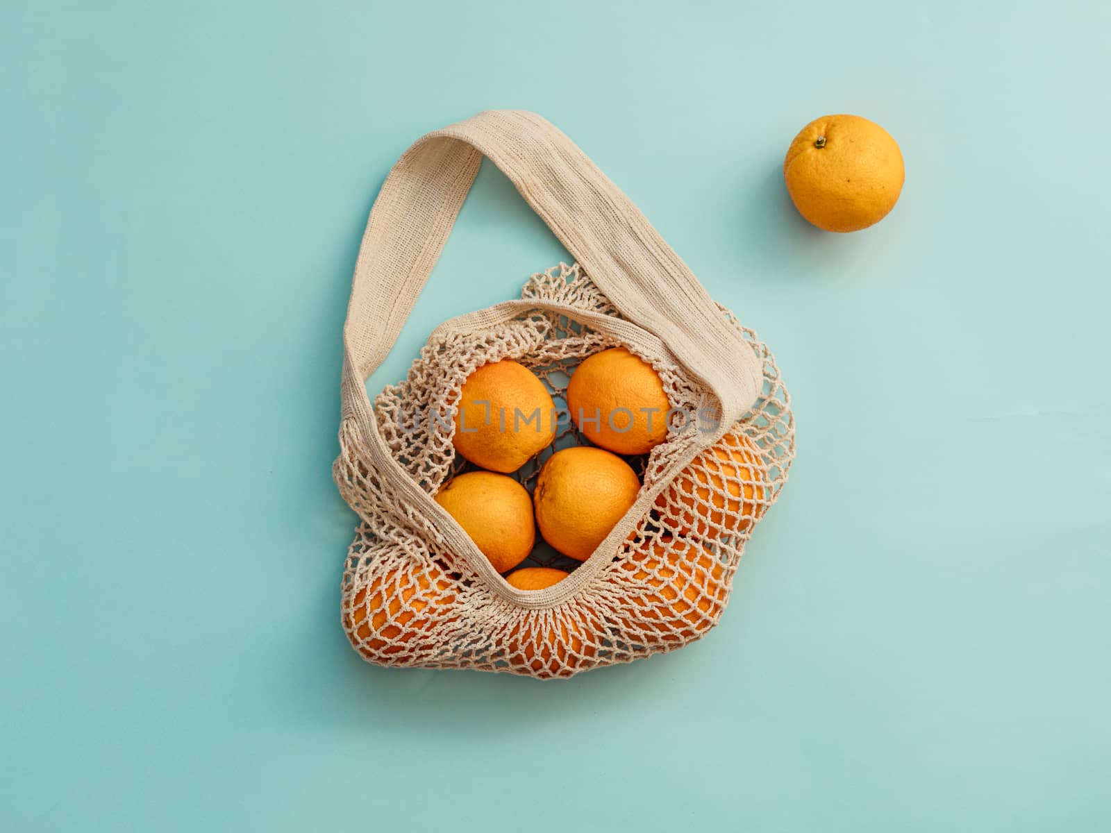 Mesh bag with fruits on blue background. Modern reusable shopping and zero waste concept.