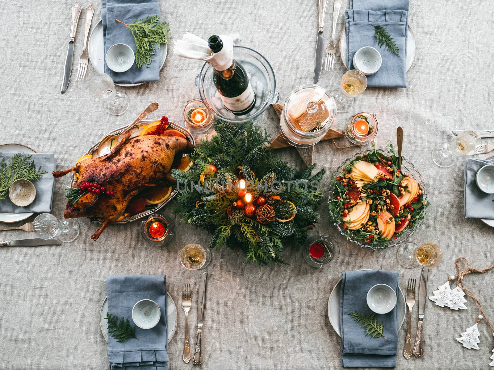 Top view of table served for Christmas dinner. Beautiful served table with salad, backed duck, decorations, fir branches. Holiday setting