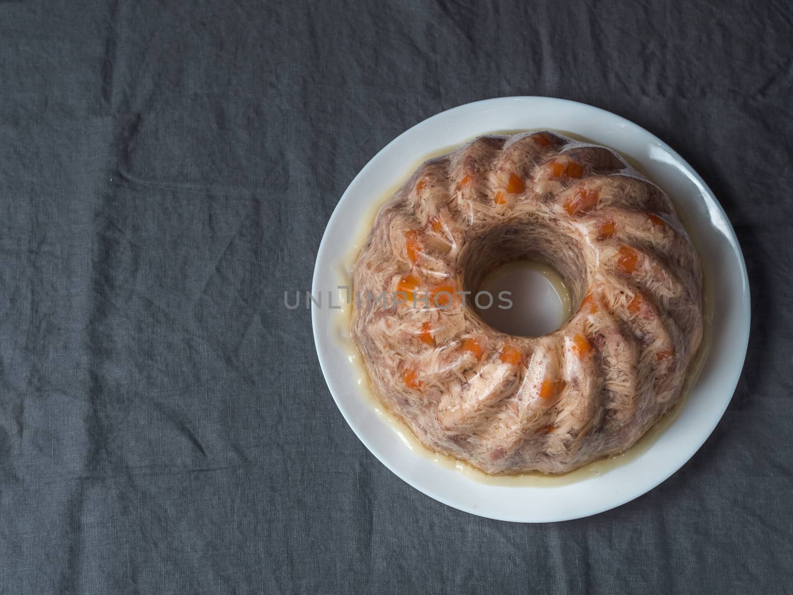 Homemade delicious jelly meat on table with dark gray linen tablecloth. Perfect jellied meat, aspic, galantine with carrot. Copy space for text. Top view or flat lay.